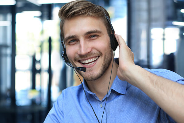 Homme souriant répondant au téléphone - Améliorer sa communication par téléphone